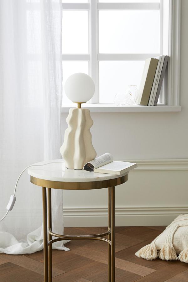 Esta mesa auxiliar redonda de metal dorado con tablero de mármol en blanco tiene una altura de 55 centímetros y un diámetro del tablero de 40. Su precio es de 129 euros.