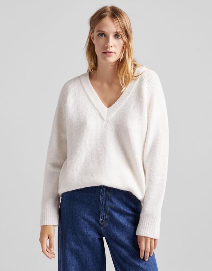 Disponible en color arena, blanco o negro, este jersey de cuello de pico de Bershka y diseño oversize podemos encontrarlo entre las tallas XS y XL por 22,99 euros. 