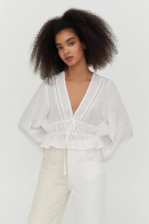 Este blusón blanco con detalle de puntilla y escote de pico cuenta con goma en la cintura y tiene un precio de 19,99 euros. Es de Pull & Bear.