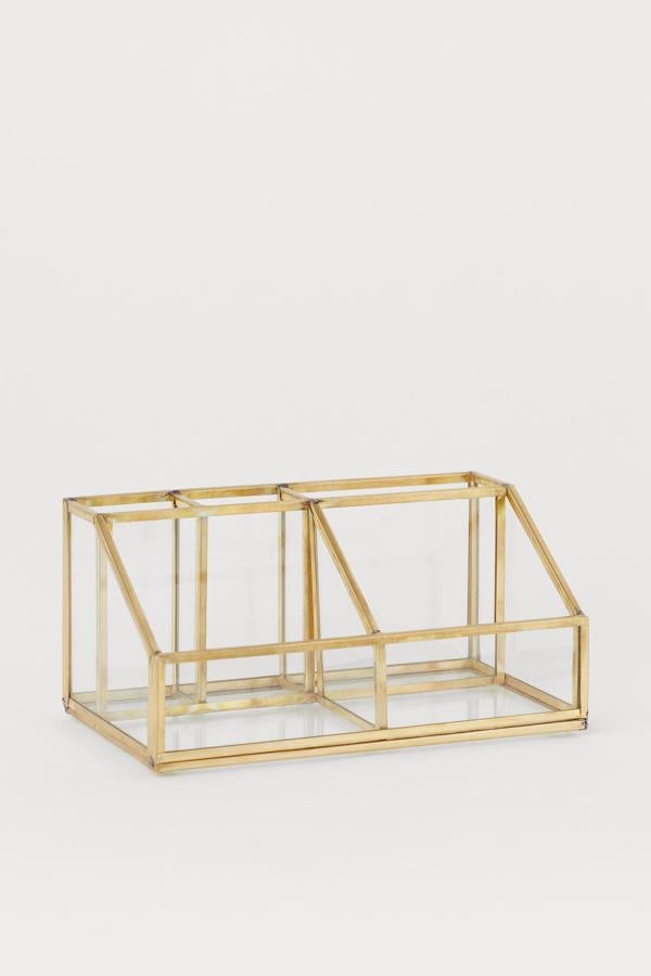 Disponible en metal dorado o en negro, este organizador con laterales de vidrio transparente cuenta con varios compartimentos y tiene un precio de 19,99 euros.