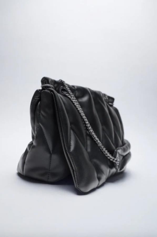 En formato bandolera, con cuerpo acolchado y detalle de pespunte, este bolso negro de Zara con asas de hombro tipo cadena y cierre de solapa con imán cuesta 29,95 euros. 