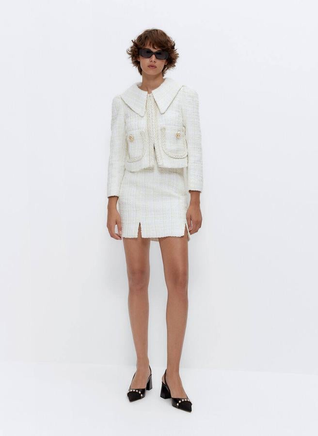 Conjunto de chaqueta y falda mini en tono crudo con detalles de botones dorados de Uterqüe. Se vende por separado. Chaqueta por 159 euros y falda por 79 euros.