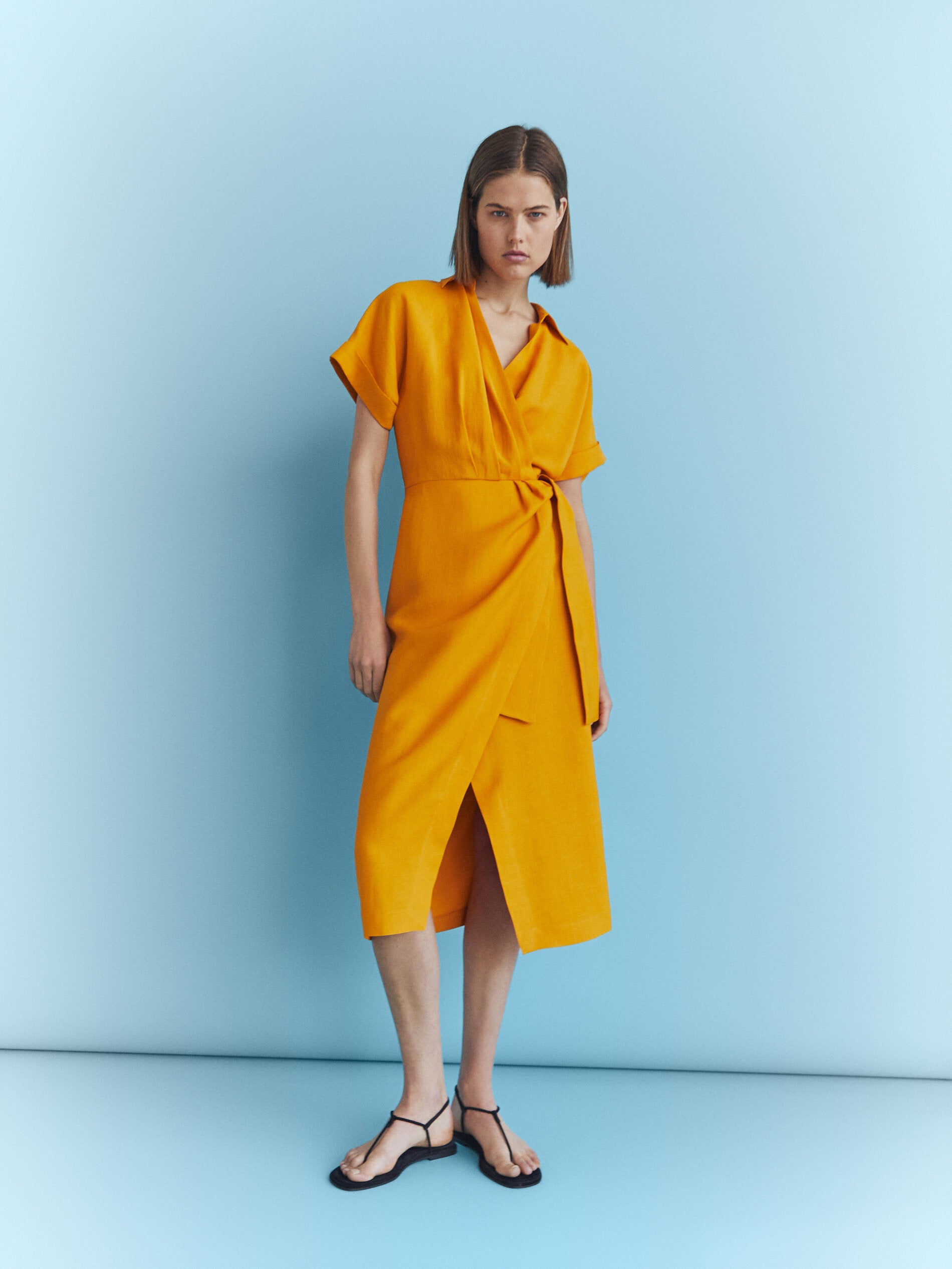 En Massimo Dutti encontramos este favorecedor vestido camisero de silueta wrap con lazo en un favorecedor tono anaranjado. Cuesta 89.95 euros.