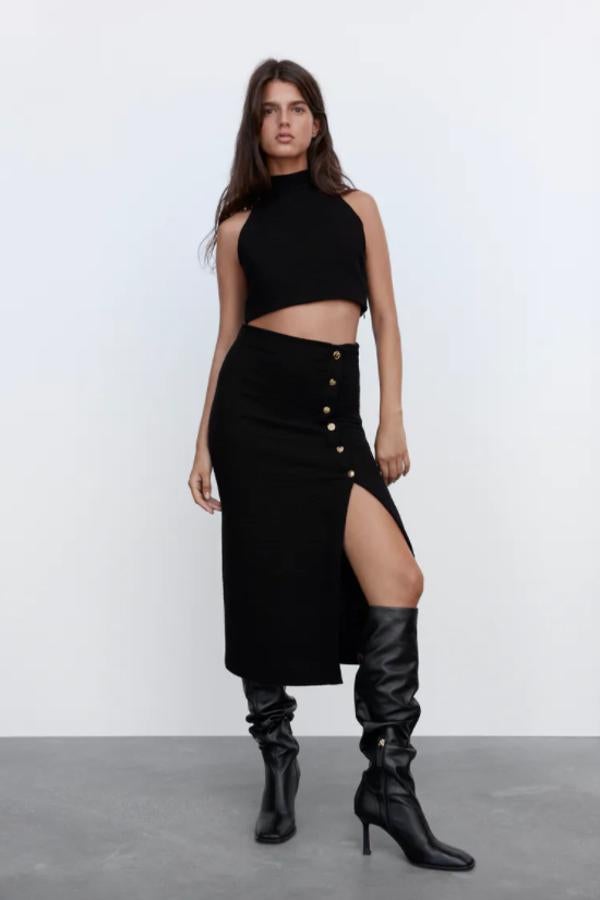 En color negro y con detalle de botones metálicos con relieve en delantero para esta falda midi de tiro alto de Zara con bajo acabado en abertura por encima de la rodilla. Disponible entre las tallas XS y XXL por 39,95 euros. 