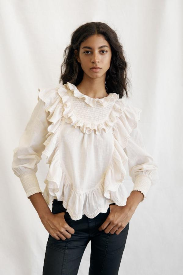 Las blusas blancas también llegan con nuevas propuestas. Con el bajo asimétrico y cubierta de volantes, nos recuerda al estilo de Isabel Marant. Blusa en color crudo de Sfera (25,99 euros) 