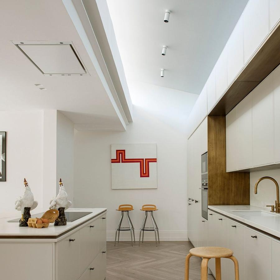 La cocina destaca por el color blanco en todos los muebles. El toque cálido lo aportan los detalles en madera, y la grifería en tonos dorados.