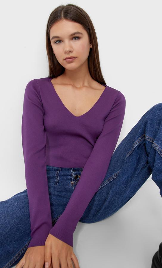 En punto fino, con escote de pico y mangas largas, este jersey morado de Stradivarius cuesta 12,99 euros y está disponible entre las tallas XS y XL. 