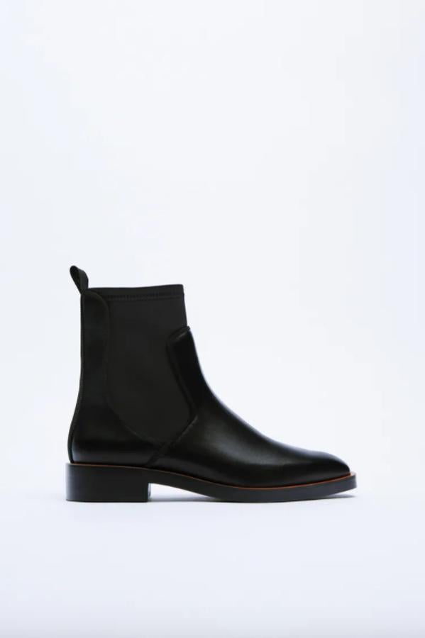 En color negro y con tacón de 2,5 centímetros, este botín plano de Zara con caña elástica a tono y tirador en la parte trasera tiene un precio de 29,95 euros y está disponible entre los números 37 y 42. 