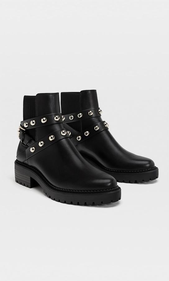 Con tiras con tachas metalizadas y hebilla sobre el tobillo estos botines negros de Stradivarius con elástico y suela track cuestan 35,99 euros y están disponibles entre los números 35 y 41.