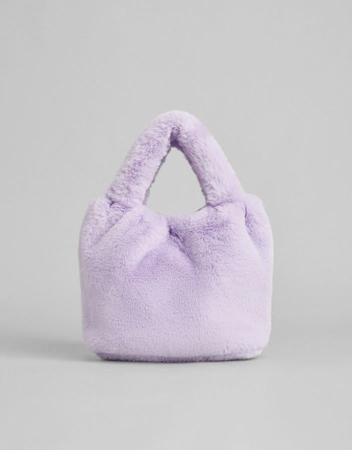 Diseño tipo bombonera con cuerpo y asa en efecto pelo en color lila para este bolso de mano de Bershka que cuesta 19,99 euros. 