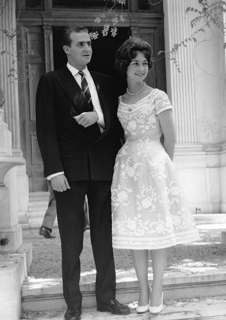 Pocos días antes de  su boda en Atenas , la Princesa Sofía de Grecia posó con este maravilloso vestido blanco con encajes bordados, cuello barco y silueta 'new look' con su prometido, don Juan Carlos de Borbón, que por aquel entonces llevaba el brazo en cabestrillo.