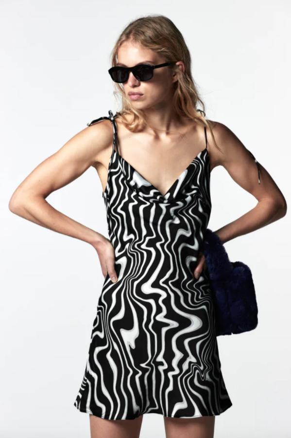 Con escote fluido y tirantes finos ajustados con lazada, este vestido corto con estampado fantasía en tonos negros y blancos costaba 25,95 euros y ahora podemos comprarlo por 15,99 euros. 