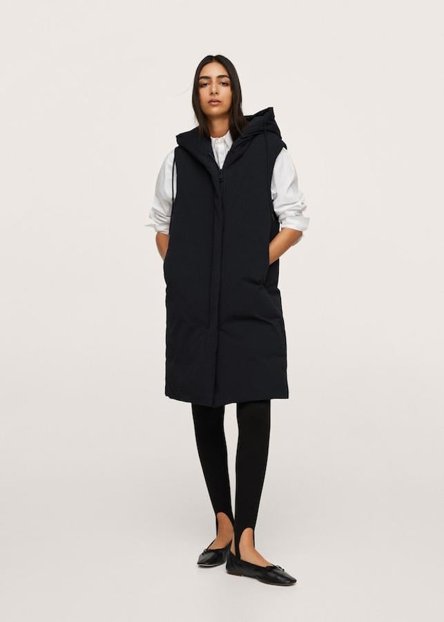 En color negro y confeccionado en tejido water repellent, este chaleco acolchado de Mango de diseño oversize con capucha ajustable y dos bolsillos laterales de cremallera viene con cierre frontal de cremallera y cuesta 79,99 euros. Solo queda en la talla XS. 