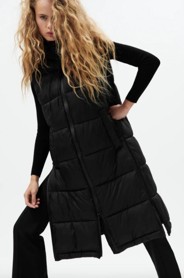Cuello subido con capucha para este chaleco acolchado negro de Zara que viene con bajo con aberturas laterales, cremallera termosellada en el frontal y bolsillos en delantero. Disponible entre las tallas XS y L, cuesta 49,95 euros. 