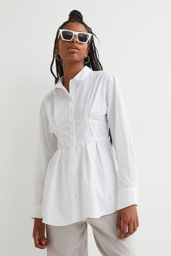 En H&M hemos encontrado esta camisa en popelín de algodón que viene con pliegues moldeadores bajo el busto y en la cintura. Tiene cuello clásico, tapeta de botones frontal y hombros ligeramente caídos con cintura entallada. Solo queda en las tallas L y XL y cuesta 19,99 euros. 