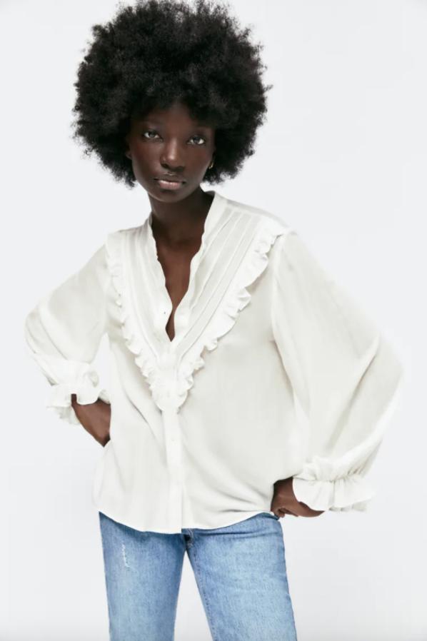 Esta camisa en blanco roto de Zara viene con cuello redondo con mangas largas acabado en elástico con volante, cierre frontal de botones y detalle de jaretas y volantes delanteros. Disponible entre las tallas XS y XL, tiene un precio de 29,95 euros. 