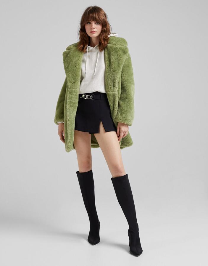 Disponible en verde, camel y negro, este abrigo en efecto pelo de Bershka con bajo por encima de la rodilla y cuello de solapa con muesca tiene bolsillos laterales y cierre frontal de botones a contraste. Podemos encontrarlo entre las tallas XS y L por 59,99 euros. 