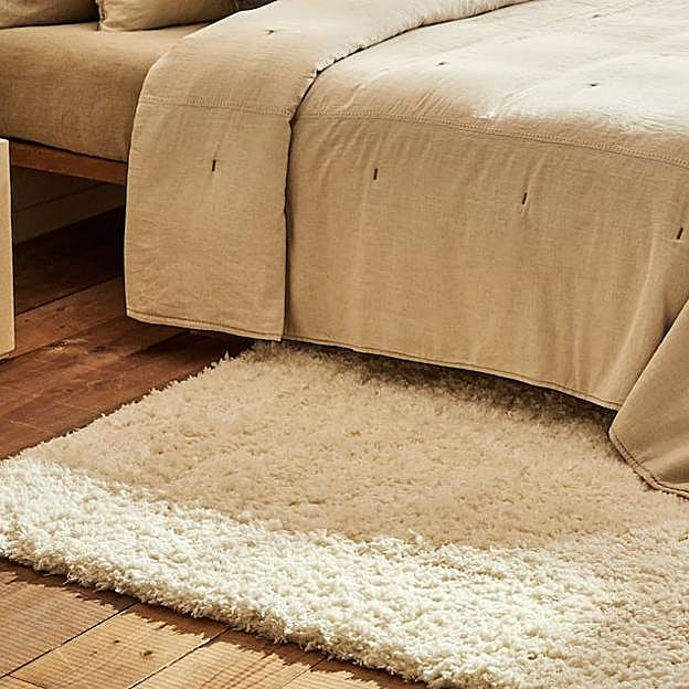 Imagen principal - La alfombra depelo está disponible desde 49.99 euros, el edredón, 79.99 euros; la lámpara de cerámica cuesta 79.99 euros y el espejo de pie, 99 euros.