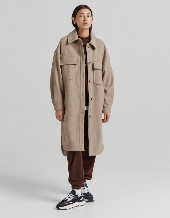 Diseño liso en color camel para esta sobrecamisa larga de Bershka confeccionada en efecto lana, con bolsillos de plastrón en la pechera y cierre de botones frontal. Tiene los bajos asimétricos y ligeramente redondeados y cuesta 39,99 euros.