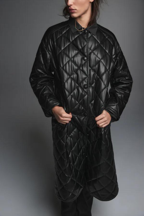 Diseño largo acochado confeccionado en suave poliuretano para este abrigo negro de Zara con cuello redondo y de corte recto oversize. Tiene cierre frontal de botones a presión forrados a tono y de 79,95 euros pasa a costar 47,97 euros. 