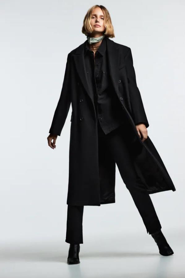 En color negro, confeccionado en tejido con mezcla de lana este abrigo largo con cuello de solapa y mangas largas con hombreras tiene bolsillos con solapa de vivo en delantero y bajo con abertura en la espalda y de 109 euros pasa a costar 65,40. 