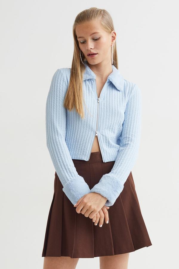 Disponible en negro, azul celeste y marrón, este cárdigan con cuello y puños en pelo sintético y cierre frontal de cremallera metalizada tiene bajo recto y está confeccionado en punto suave de canalé. Podemos comprarlo en H&M por 19,99 euros. 