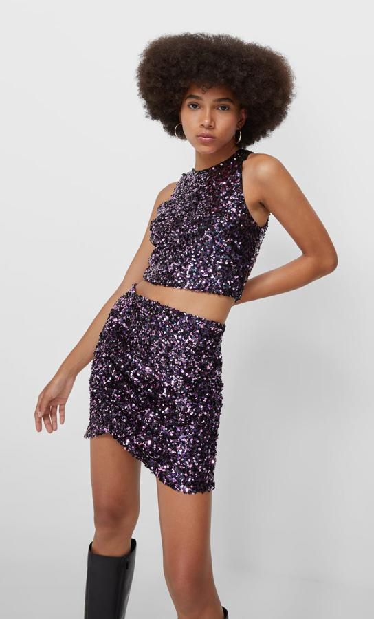 Cuello halter sin mangas para este top de Stradivarius con lentejuelas en púrpura oscuro y diseño cropped. Podemos comprarlo por 17,99 euros.