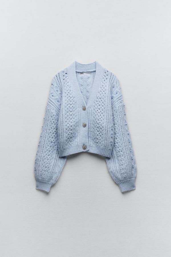 Una buena alternativa a los tops de fiesta son ñas prendas de punto con detalles especiales. Este cárdigan azul lavanda es perfecto para los planes más informales. Chaqueta calada de Zara (29,99 euros). 