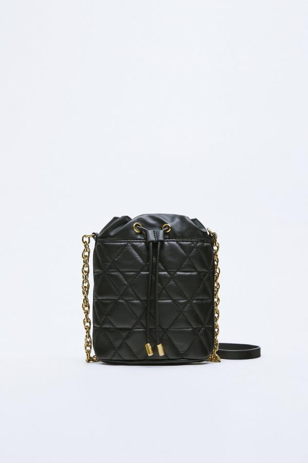 Los bolsos acolchados llegan reversionados. El de estilo bombonera es la última apuesta de Zara. Bolso negro con cadena dorada de Zara (25,99 euros). 