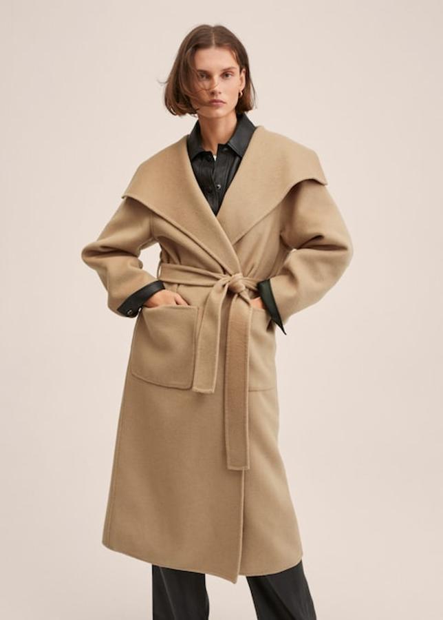 Diseño oversize para este abrigo largo de Mango en color beige, con cuello de pico con solapa, dos bolsillos de plastrón laterales y cinturón a tono que cuesta 159,99 euros. 