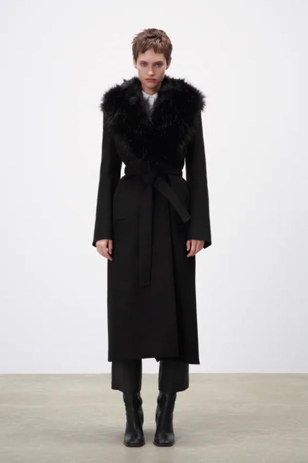 Confeccionado con tejido en mezcla de lana, este abrigo negro de Zara que viene con cuello de solapa con aplicación efecto pelo extraíble y cinturón de lazada a tono tiene mangas largas acabadas en abertura y botones y cuesta 129 euros. 