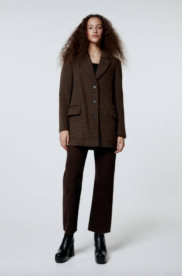 Estampado pata de gallo en tonos marrones y negros para esta blazer confeccionada en tejido con mezcla de lana que viene con cuello de solapa con muescas, mangas largas con hombreras y bolsillos con solapa en los laterales y al bies en la pechera. Cuesta 49,95 euros.