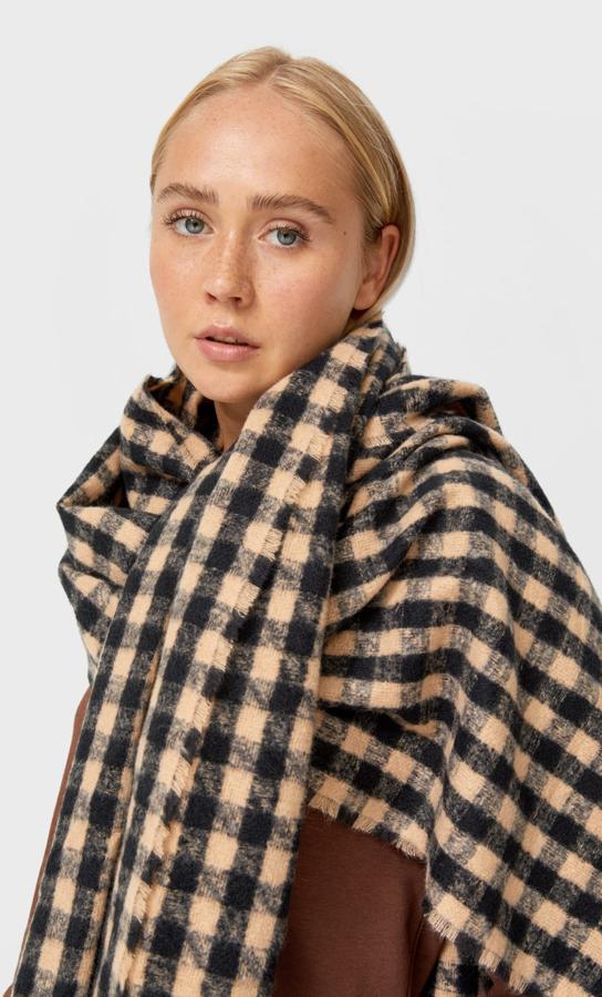 Acabado desflecado para esta bufanda de Stradivarius con estampado damero en beige y negro que está rebajada y de 12,99 euros ha pasado a costar 9,99 euros. 