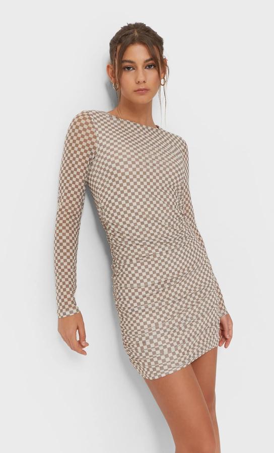 En tul y color piedra, este vestido con estampado damero de Stradivarius de diseño mini, con mangas largas y cuello redondo cuesta 19,99 euros. 