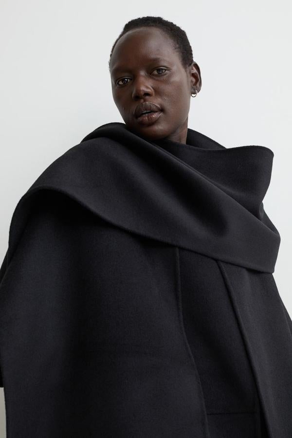 Este abrigo negro confeccionado en mezcla de lana suave con bufanda ancha extraíble es de H&M y viene con diseño de corte relajado con hombros marcadamente caídos, bolsillos en las costuras laterales y aberturas laterales en el bajo. Tiene un precio de 129 euros. 