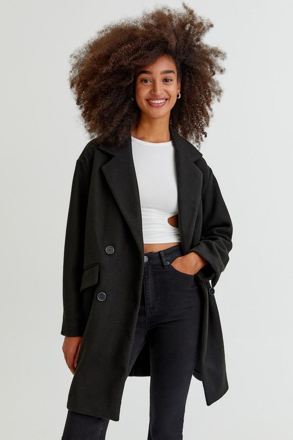 Con cierre cruzado de botones a tono, cuello de solapa con muesca y bolsillos delanteros de tapeta, este abrigo negro de Pull&Bear tiene un precio de 29,99 euros. 