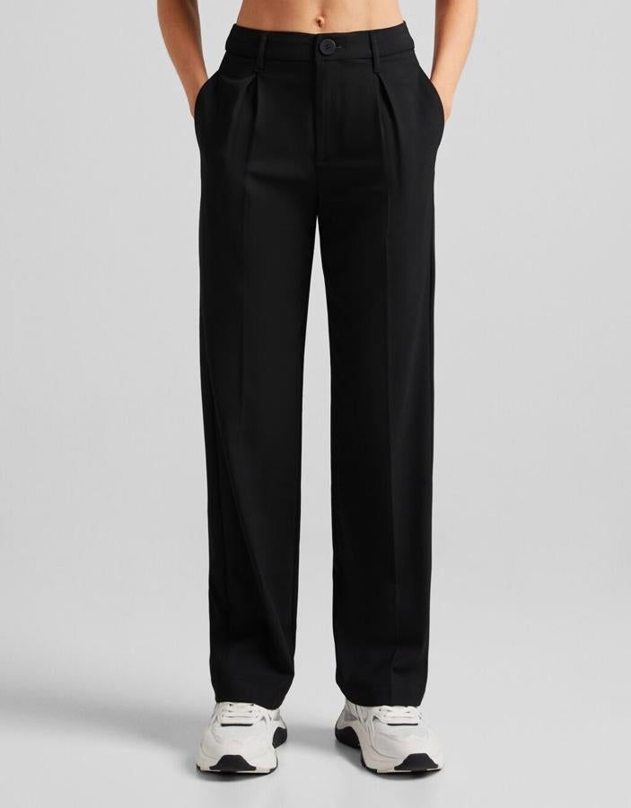 Con pinzas frontales y diseño recto, estos pantalones negros de Bershka con bolsillos laterales y cintura con cierre de botón cuestan 22,99 euros. 