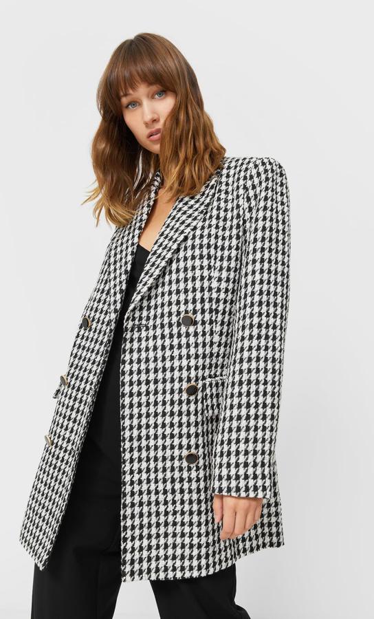 Estampado pata de gallo en blanco y negro para esta americana de Stradivarius con cuello de solapa, mangas largas y hombros marcados. Tiene el cierre frontal cruzado con botones en negro y puños abotonados y cuesta 35,99 euros. 