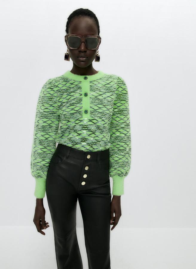 En verde lima y con efecto relieve metalizado, este jersey de punto jacquard de Uterqüe es de cuello redondo y viene con cierre de botones joya en el escote. Podemos comprarlo por 89 euros. 