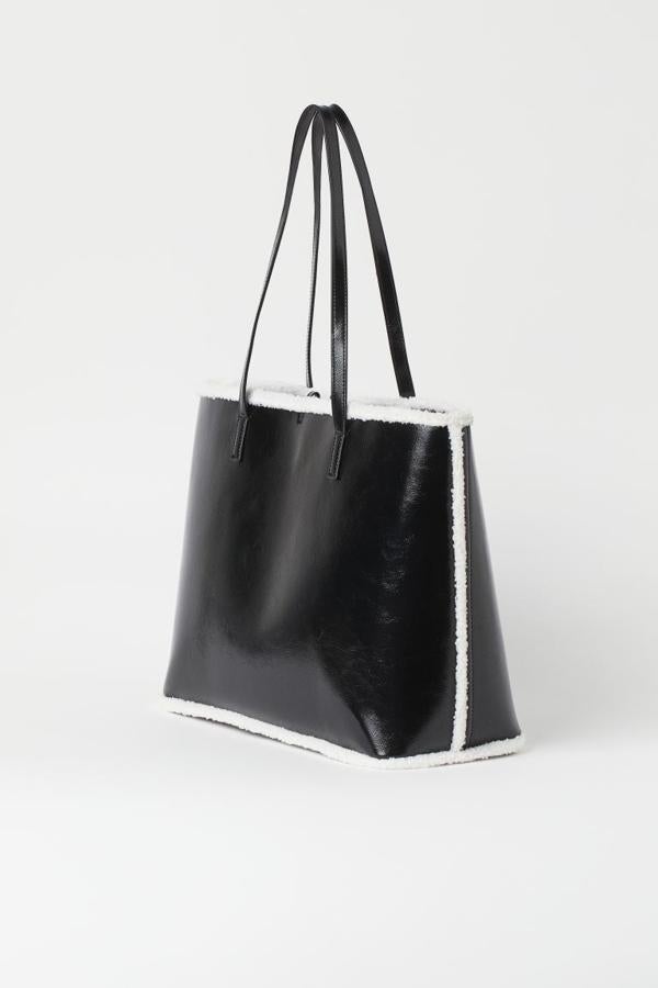 Con detalles de borreguillo a contraste en blanco, este bolso shopper con exterior de piel sintética e interior de ante sintético es de H&M y viene con doble asa de hombro a tono. Solo se vende online y de 19,99 euros ha pasado a costar 12,99 euros. 