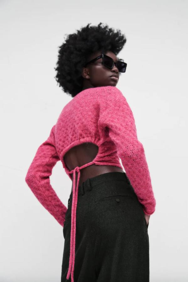 Espalda abierta con lazo, cuello redondo y mangas largas para este jersey de punto en color rosa que podemos comprar por 25,95 euros. 