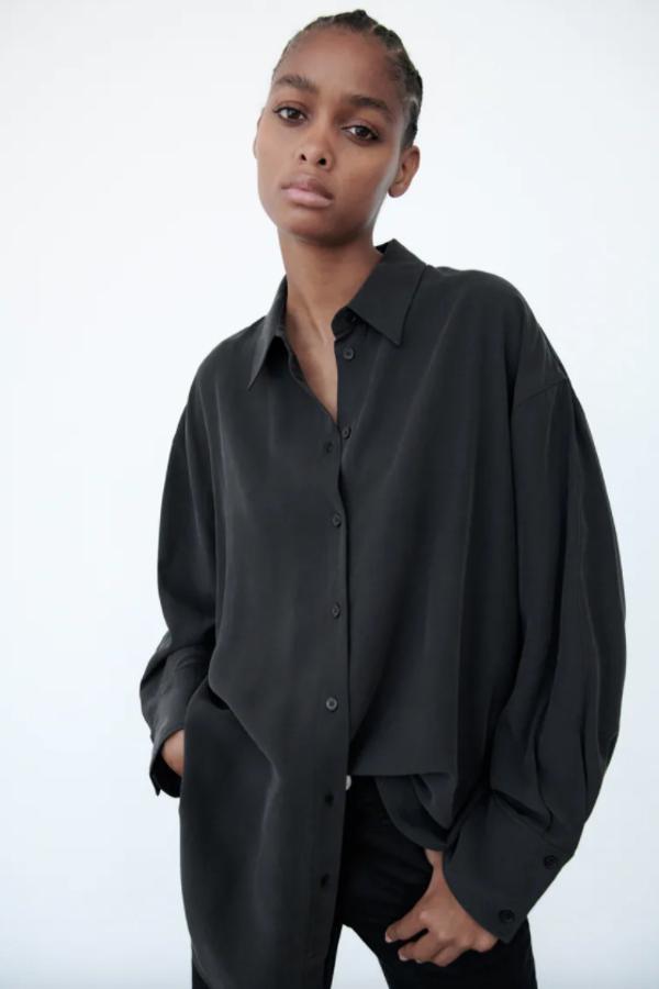 Esta camisa soft en color negro es de Zara y viene con cuello de solapa con mangas largas acabadas en puño con pliegues y bajo acabado con aberturas laterales. Con cierre frontal de botones, podemos encontrarla entre las tallas XS y XXL, menos en la M, por 25,95 euros. 