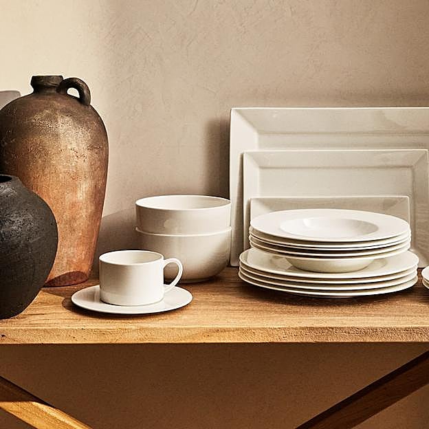 Imagen principal - La vajilla blanca de loza está disponible en Zara Home desde 3.99 euros la pieza, la bandeja de madera cuesta 19.99 euros y las piezas de cristalería de vidrio textirizado de colores, desde 5.99 euros.