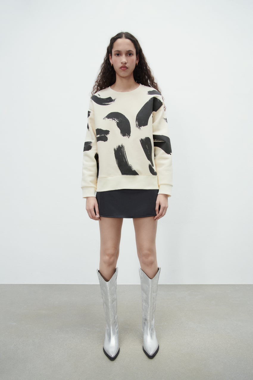 En color crudo con print de brochazos en negro, esta sudadera de Zara con cuello redondo y mangas largas cuesta 22,95 euros. 