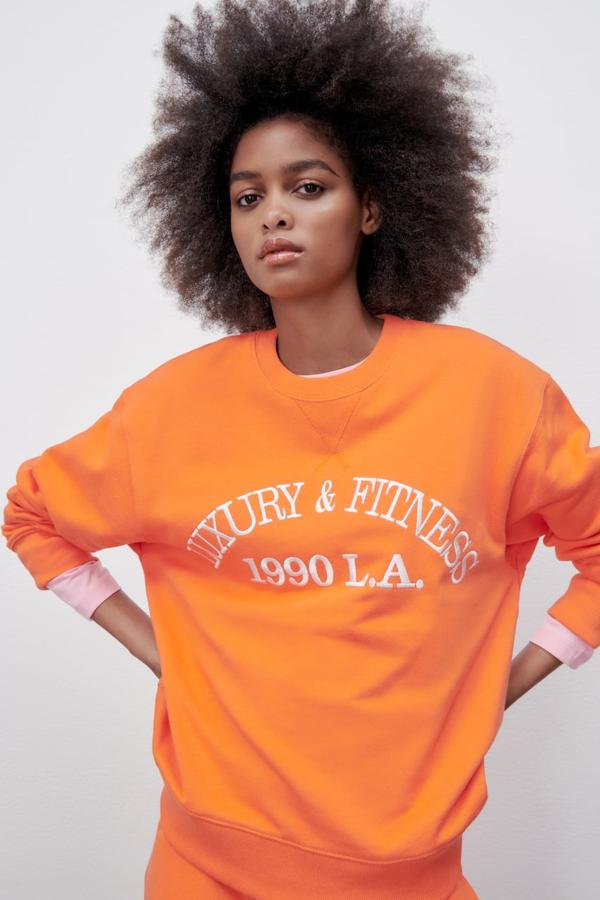 Cuello redondo, acabados en rib y mangas largas para esta sudadera naranja con texto frontal a contraste en blanco que podemos encontrar en Zara por 25,95 euros. 