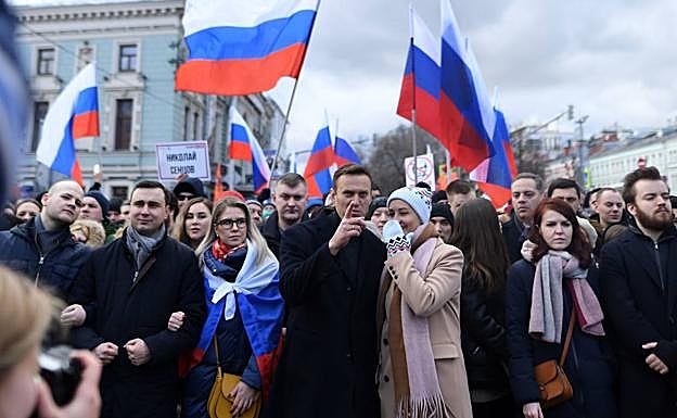 Sobol, con la bandera rusa sobre los hombros, junto a Navalni y su mujer, Julia, en una marcha en Moscú en febrero de 2020, en memoria del opositor asesinado Boris Nemtsov.
