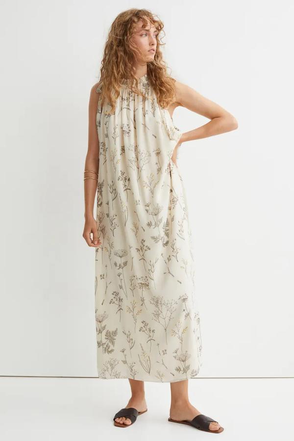 Estampado floral en tonos amarillos y oliva para este vestido tobillero sin mangas confeccionado en tejido arrugado con caída. De cuello fruncido, con volante y lazada lateral, es de H&M y cuesta 39,99 euros.