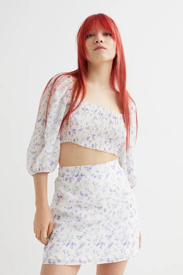 En crepé de gasa, con elástico revestido en la cintura y de color blanco con estampado de flores lilas, esta minifalda de H&M que viene con forro a tono cuesta 19,99 euros. 