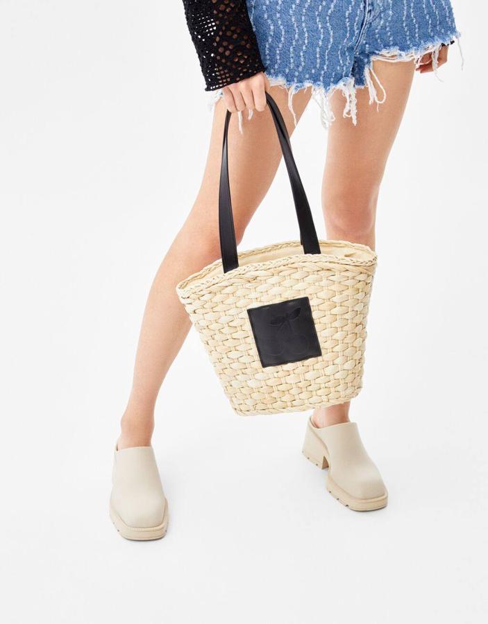 Una opción low cost muy versátil es un capazo de tamaño mini que hemos encontrado en Bershka. Es de color beige y cuenta con una doble asa en negro. Cuesta 22,99 euros.