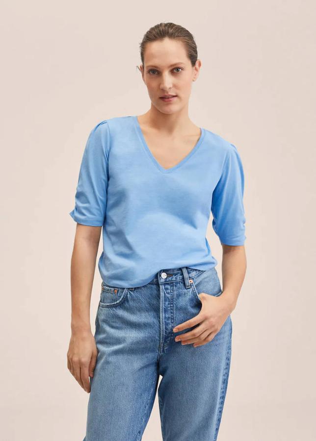 Mango nos trae un modelo de corte recto, cuello de pico y con una manga corta fruncida. La encontrarás en blanco, negro, rojo y azul. Tiene un precio de 9,99 euros.